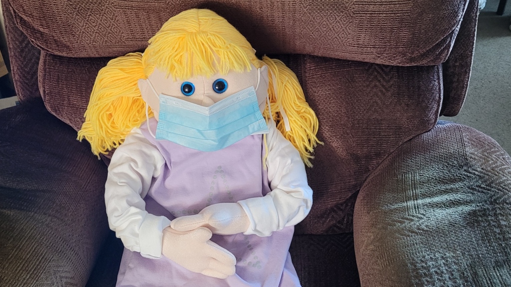 A puppet wearing a blue surgical mask