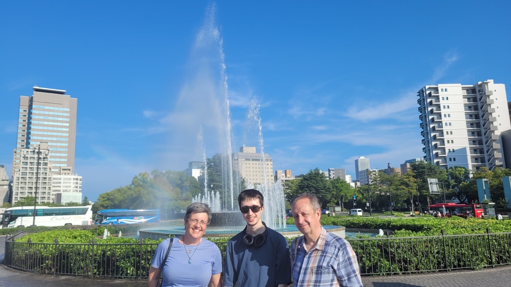 Lynnette, her husband, and her son, standing in front of a fountain in Hiroshima.